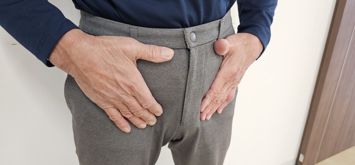 下腹部や鼠径部に違和感や膨らみを感じている男性のイメージ
